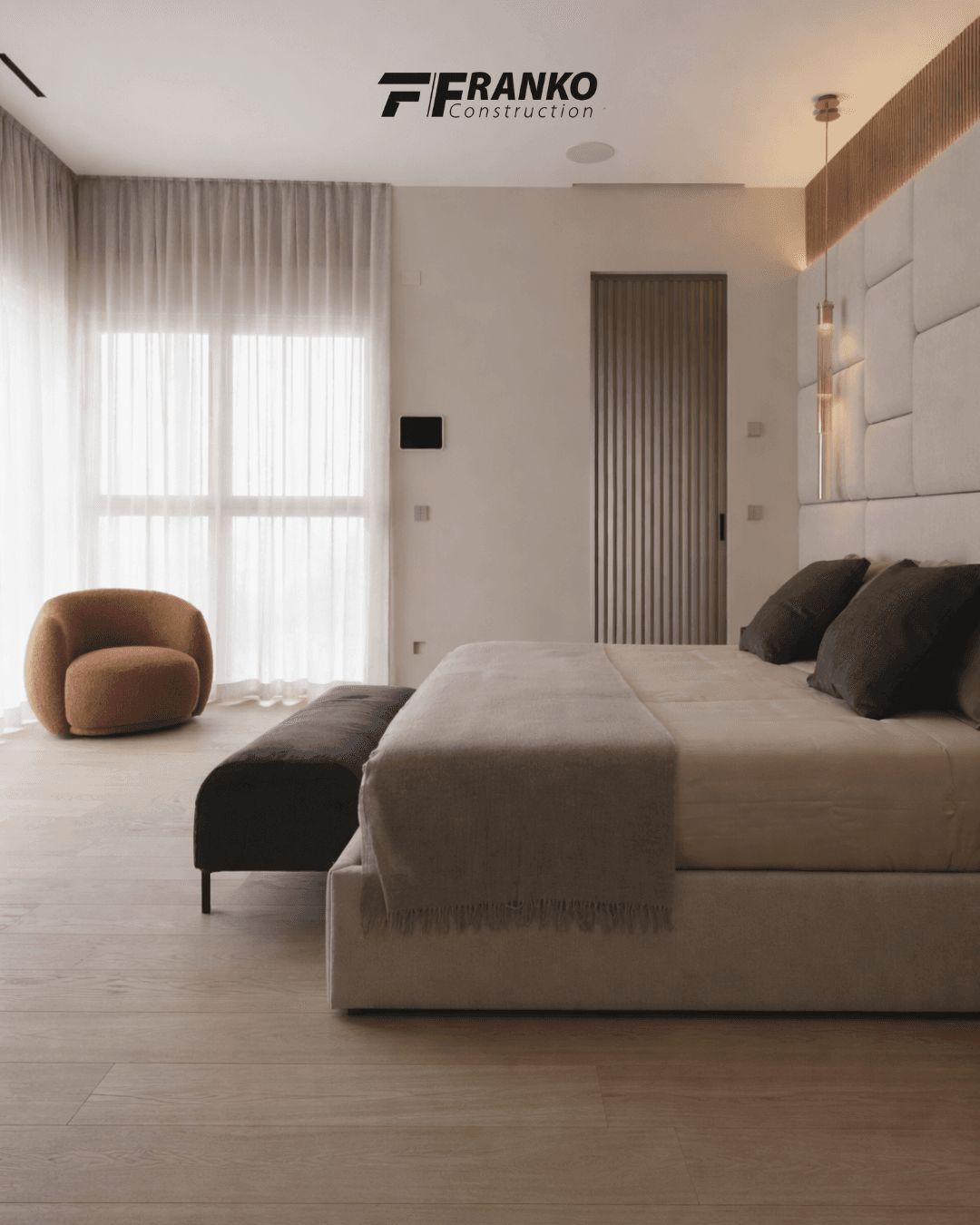 Modern bedroom with a paneled headboard, dark grey bench, and a round terracotta armchair.